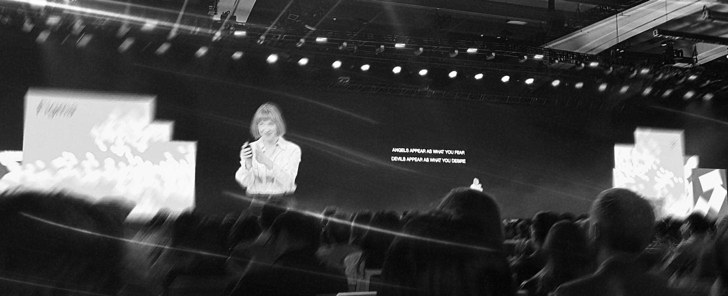 Speaker on stage with the quote angels appear as what you fear, devils appear as what you desire